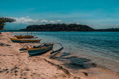 Boat moored on beach against sky