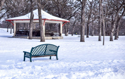 Empty bench by gazebo at snow covered park