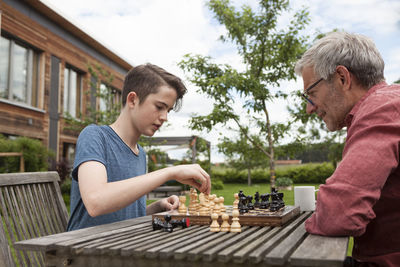 Father and son playing chess in garden