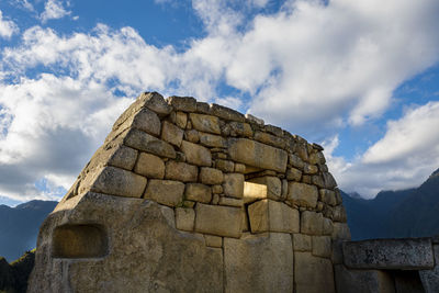 Low angle view of stone structure against cloudy sky