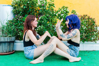 Happy young women playing patty cake in backyard