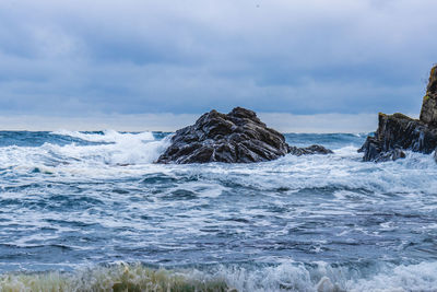 Scenic view of rocks in sea against sky