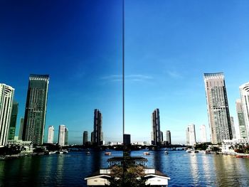 River by modern buildings against blue sky