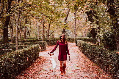 Full length portrait of young woman walking on footpath in forest