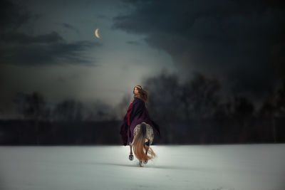 Full length of young woman with horse in snow