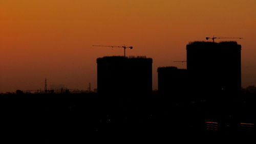 Silhouette buildings against sky during sunset