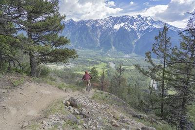 Rear view of man walking on landscape against mountains