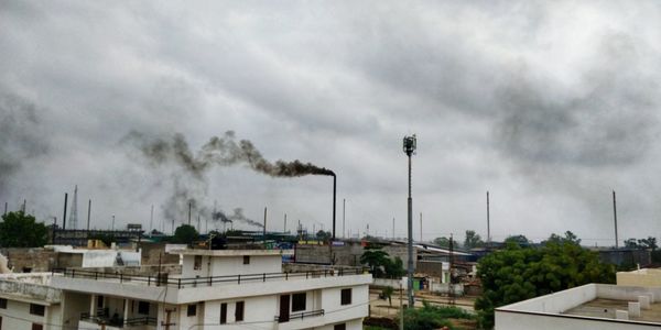 Smoke emitting from factory against sky