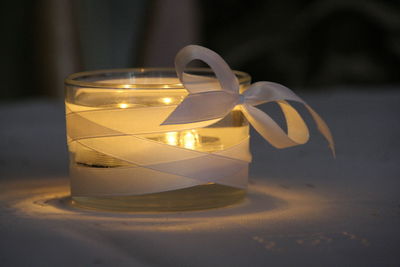 Close-up of illuminated lighting equipment covered with ribbon on table