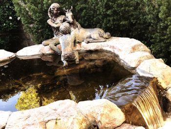 Statue on rock by lake