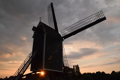 Low angle view of traditional windmill against sky during sunset