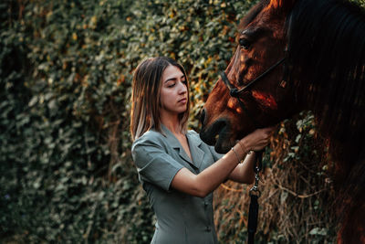 Close-up of young woman standing with horse outdoors