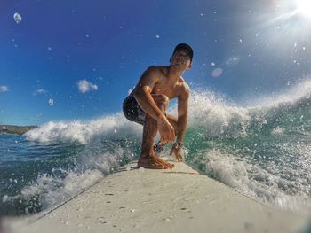 Side view of shirtless man surfing on breaking wave