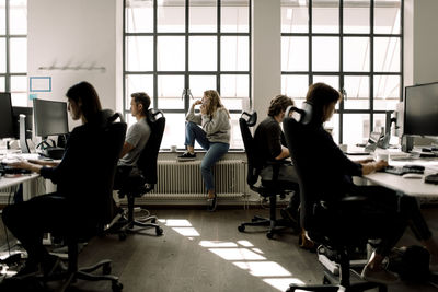 Coworkers working while female talking on phone in office