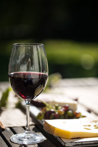 Close-up of red wine and cheese on wooden table