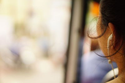 Close-up of woman listening music by window