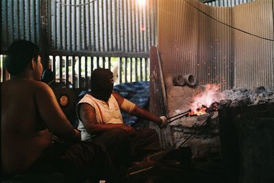 Rear view of people sitting on barbecue grill