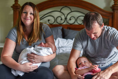 Parents with children sitting on bed at home