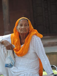 Senior woman sitting against building