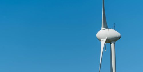 Low angle view of wind turbine against clear blue sky