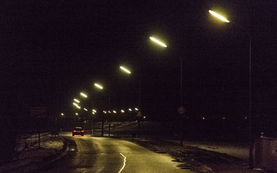 Cars on illuminated road against sky at night