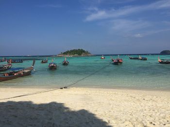 Sailboats moored on beach against sky