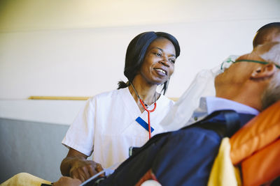 Smiling female doctor looking at mature patient on stretcher in hospital