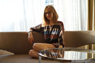 Young woman sitting on sofa at home