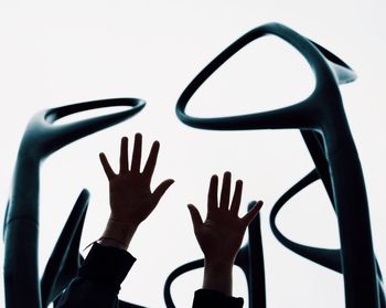 Cropped hands of woman amidst outdoor play equipment against sky