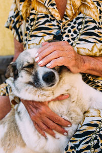 A very old smartly dressed woman stroking her jet dog outside the house