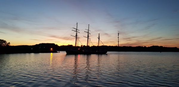 Silhouette sailboats on lake against sky during sunset