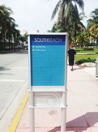 Information sign on footpath by palm trees