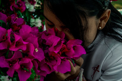 Close-up of girl with smelling pink flowers