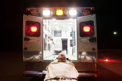 Patient lying on hospital gurney by ambulance