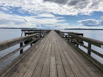 Empty wooden pier on sea against sky