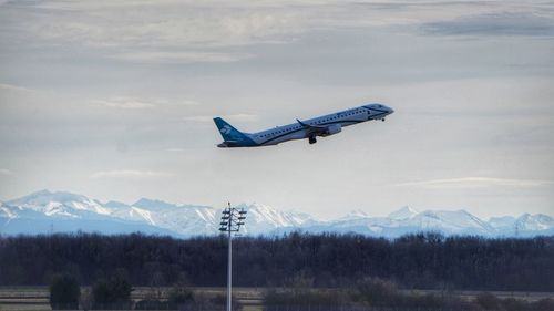 Airplane flying over mountains against blue sky