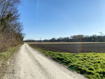 Dirt road along landscape and against blue sky