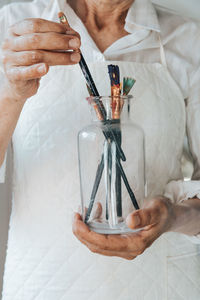 Woman removing paintbrush from bottle