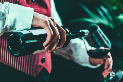 Midsection of man pouring wine in wineglass