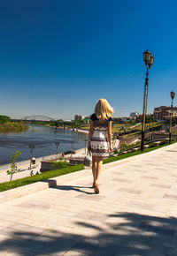 Rear view of woman in water against clear blue sky