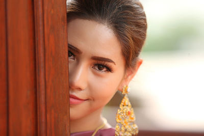 Portrait of smiling young woman hiding behind door