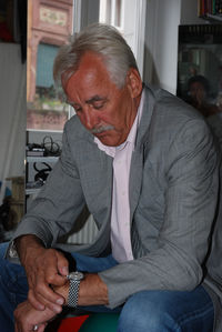 Man adjusting wristwatch while sitting at home