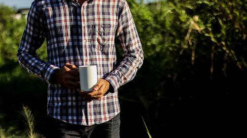 Midsection of man holding ice cream standing outdoors