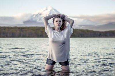 Young woman standing in sea against sky