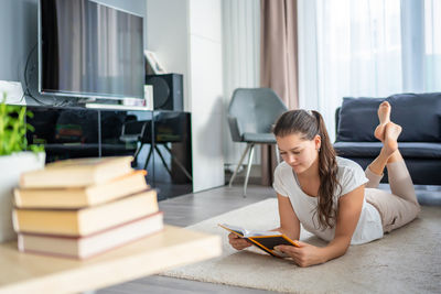 Side view of young woman using mobile phone while sitting at home