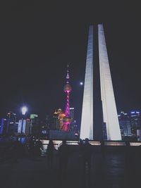 People at illuminated city against sky at night