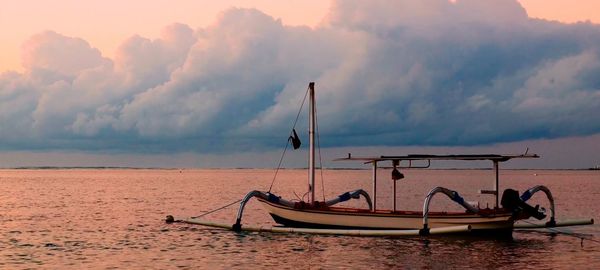 Boat moored in sea against sky during sunset