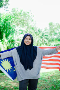 Muslim woman happy holding a malaysian flag. malaysia independence day.