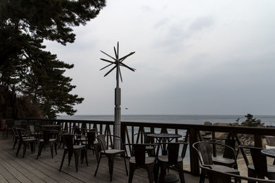 Chairs and table by sea against sky