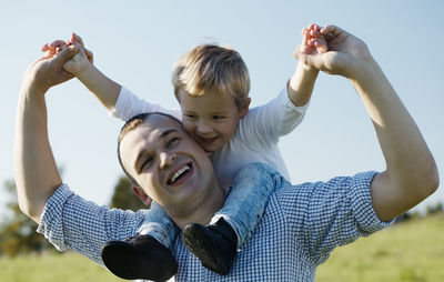 Cheerful father and son against sky